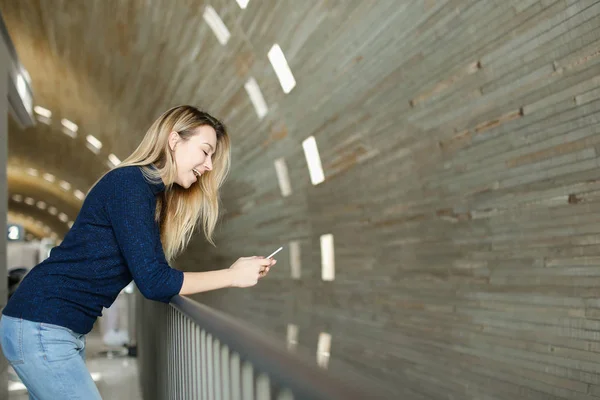 Chica rubia usando smartphone en fondo monofónico . — Foto de Stock