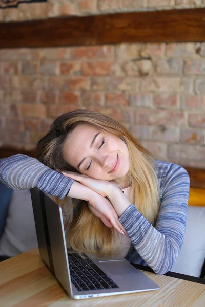 Hermosa chica durmiendo cerca del ordenador portátil en la cafetería . — Foto de Stock