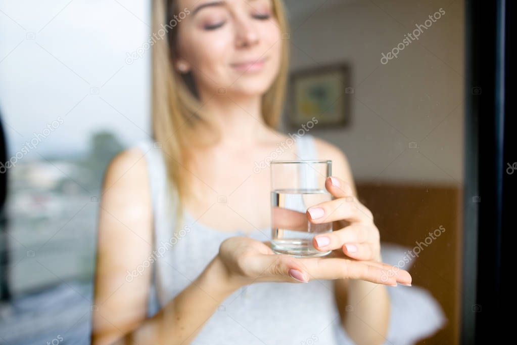 Girl keeping glass of water, blurred background.