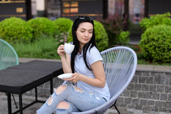 Mujer morena bebiendo café y descansando en silla con fondo verde . — Foto de Stock