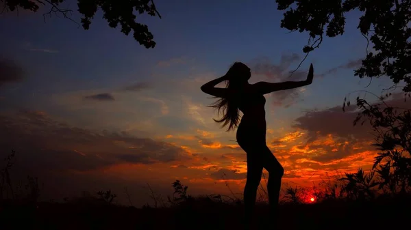 Svarta kvinnliga siluett som mediterar i kväll och gör yoga i solnedgången bakgrunden. — Stockfoto