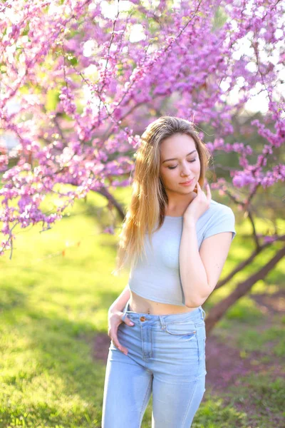 Bionda donna in piedi nel parco con sfondo in fiore . — Foto Stock