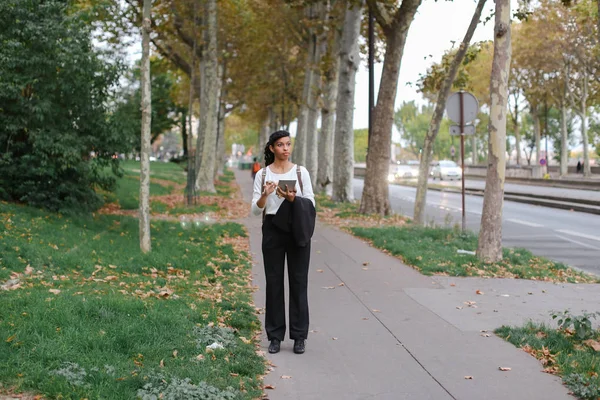 Afroamerikanische Studentin läuft mit Tablet im Herbstpark und trägt Rucksack. — Stockfoto