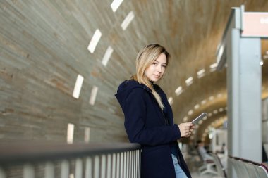 Smartphone ile tek sesli arka planda duran, koyu ceket giyen kadın.