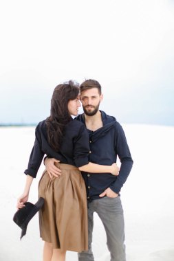 Birbirlerine sarılma ve tek sesli kış arka planda moda giysiler giyen genç mutlu çift.