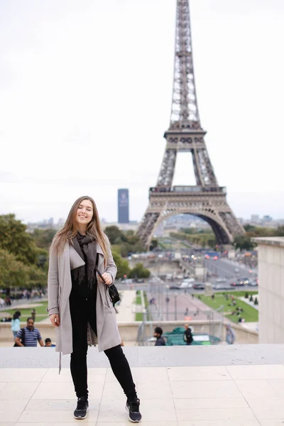 Caucasian young woman in grey coat standing with Eiffel Tower background in Paris. — Stock Photo, Image