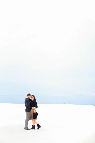 Feliz casal em pé no inverno branco fundo monofônico e abraço . — Fotografia de Stock