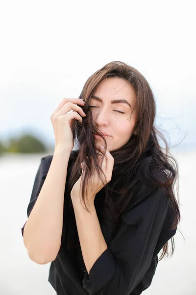 Caucasian young female person wearing black shirt standing in white monophonic background. — Stock Photo, Image