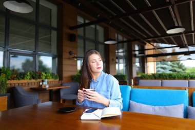 Kız öğrenci smartphone, defter ve kahve ile Café'de dinlenme.