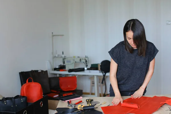 Young woman making red leather wallet at atelier. — Stock Photo, Image