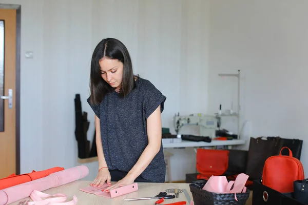 Young woman making pink leather wallet at home atelier. — Stock Photo, Image