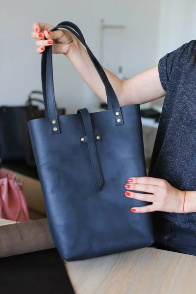 Persona femminile con manicure mantenere donna nera borsa in pelle fatta a mano in atelier . — Foto Stock