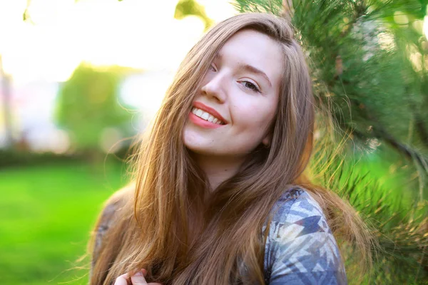 Χαμογελαστό κορίτσι κοντά ξύλο κέδρου με φόντο πράσινο γρασίδι. — Φωτογραφία Αρχείου