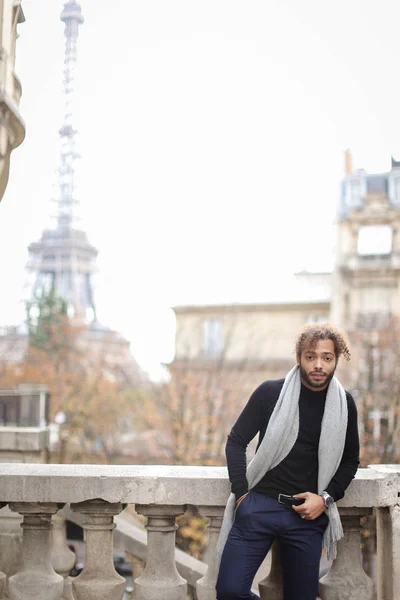 Hombre nigeriano medio americano de pie cerca de barandilla de hormigón con fondo de la Torre Eiffel en París . — Foto de Stock