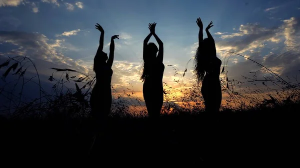 Sylwetki kobiet cień robi joga w stepie, tło zachód słońca. — Zdjęcie stockowe