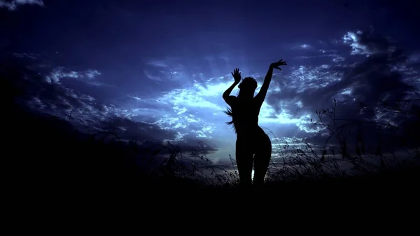 Γυναικεία μαύρη σιλουέτα στην νύχτα στέπα και γαλάζιο φόντο του ουρανού. — Φωτογραφία Αρχείου