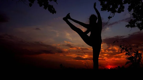 Svarta kvinnliga siluett i solnedgången bakgrunden, kvinna gör yoga innan sova. — Stockfoto