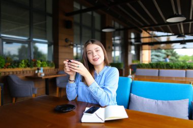 Genç kadın Café smartphone, defter ve kahve molası.