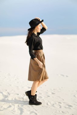 Genç kız karda, ayakta giyiyor etek, siyah bluz ve şapka, tek sesli arka plan.