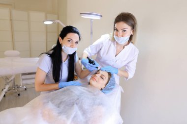 Genç kadın Başlarken profesyonel kalıcı makyaj güzellik uzmanı ve hemşire tarafından.