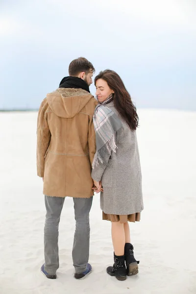 Casal jovem andando no fundo da neve de inverno, vestindo casacos e lenços . — Fotografia de Stock