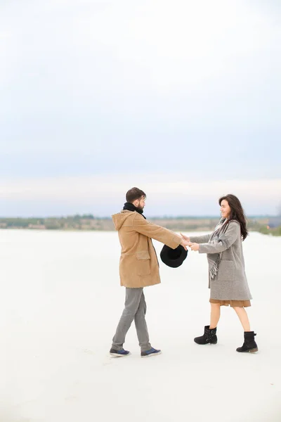 Americano y mujer yendo en la nieve y tomados de la mano, usando abrigos y bufandas . — Foto de Stock