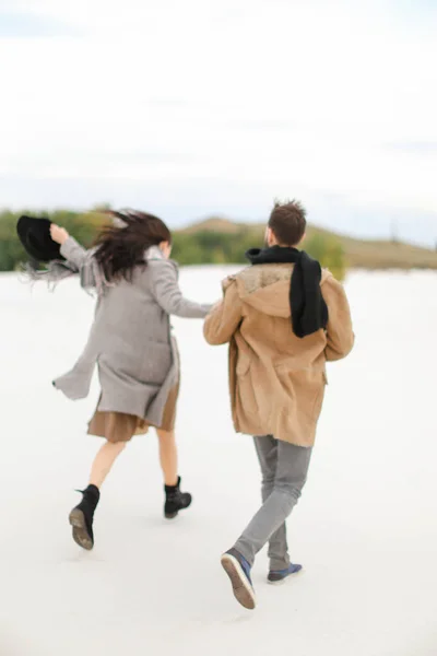 年轻的时尚夫妇走在雪和牵手, 冬天背景. — 图库照片