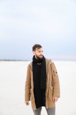 Beyaz kar arka planda ceket ve eşarp ayakta giyen Avrupa adam.