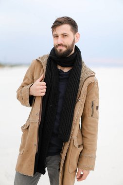 Beyaz kar arka planda sakal giyen ceket ve eşarp ayakta Kafkas genç erkek kişi.