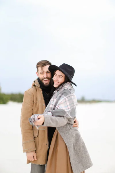 Gelukkige jonge vrouw en man dragen jassen en sjaals staande in de winter sneeuw achtergrond. — Stockfoto