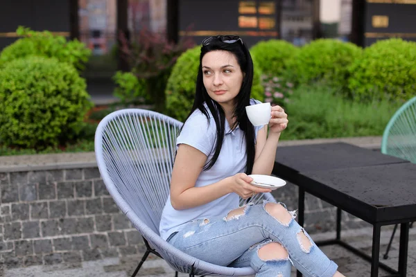 Mulher bonita bebendo café e descansando na cadeira com fundo verde . — Fotografia de Stock