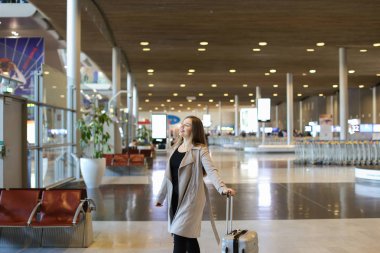 Beyaz kadın turist Havaalanı salonunda yürüyüş gri bir palto giyiyor.
