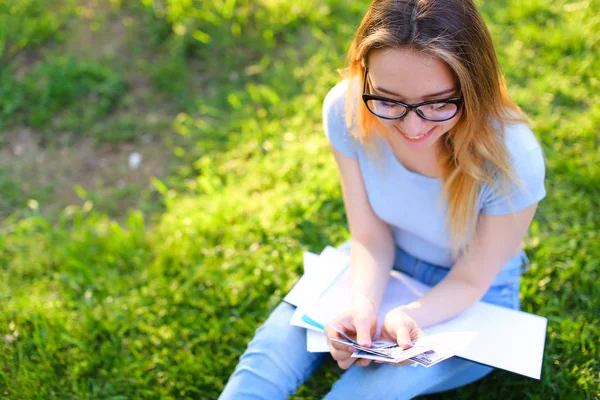 Heureux pigiste assis sur l'herbe verte avec des documents dans le parc et garder de l'argent . — Photo