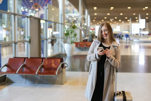 Havaalanı salonu valiz ile gidiş ve smartphone kullanarak kadın kişi.