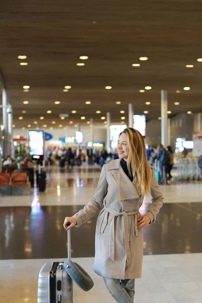 Dziewczynka stoi w poczekalni Lotnisko z valise i sobie szary płaszcz. — Zdjęcie stockowe