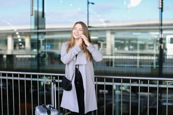 Europäerin steht mit ihrem Smartphone in der Nähe des Flughafens und spricht. — Stockfoto