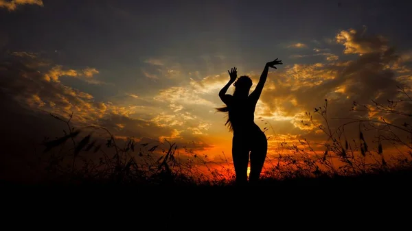 Persona femenina haciendo yoga en la estepa, silueta en el fondo del atardecer . — Foto de Stock