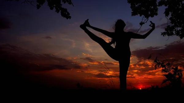 Silhouette femminile scura sullo sfondo del tramonto, donna che fa yoga prima di dormire . — Foto Stock