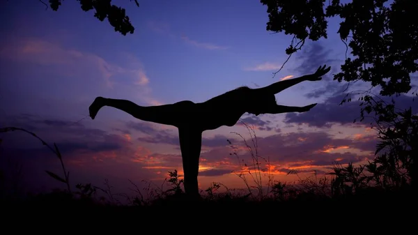 Silhouette femminile facendo yoga asana in sfondo cielo viola . — Foto Stock
