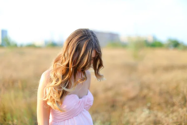 Blonde zwangere vrouw dragen van roze jurk staande in de steppe achtergrond. — Stockfoto