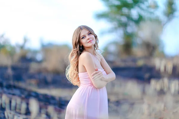 Glücklich schwangere Frau in rosa Kleid vor verschwommenem Hintergrund. — Stockfoto