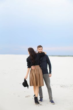 Mutlu genç gülümseyen kadın etek giyen ve şapka, kış kar arka plan tutmak hugginng adam.