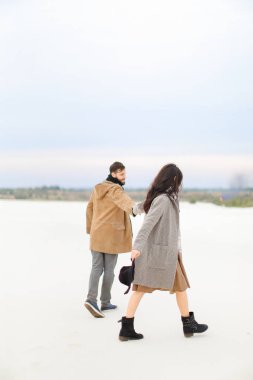 Beyaz adam ve genç kadın kar ve tutuşup, kat giyiyor ve eşarplar.