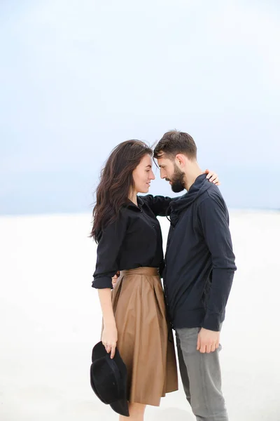 Mulher europeia bonita segurando homem e vestindo saia, mantendo chapéu em fundo de inverno branco . — Fotografia de Stock