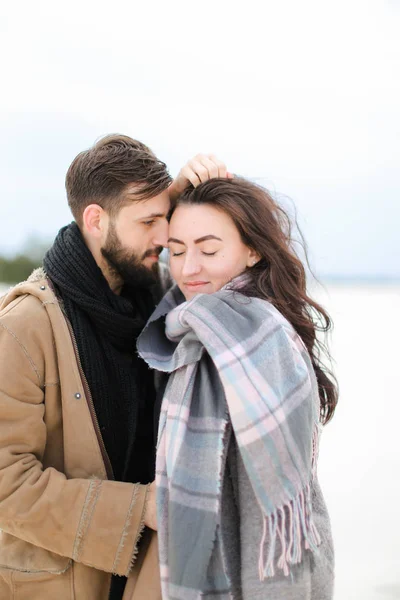 Giovane bella donna che indossa sciarpa grigia in piedi con l'uomo in cappotto, sfondo bianco invernale . — Foto Stock