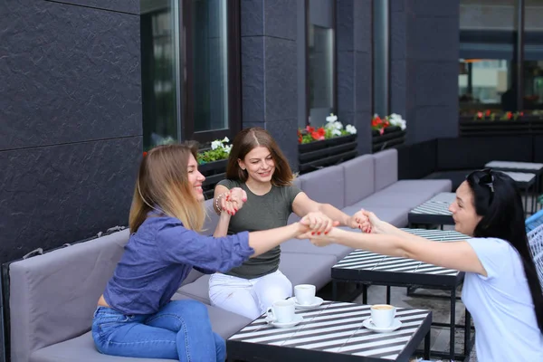 Amigas sentadas en la cafetería y cogidas de la mano . — Foto de Stock