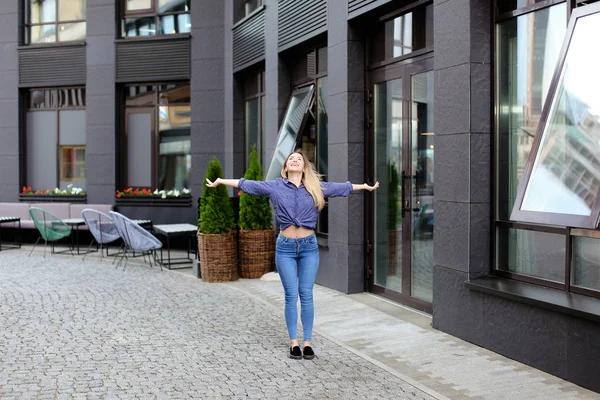 Linda chica disfrutando de caminar en la ciudad y de pie cerca del edificio . — Foto de Stock