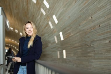 Modern smartphone ile tek sesli ışıklı arka planda duran güzel kadın kişi.