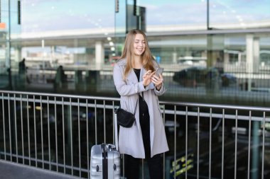 Sohbet ve smartphone valiz ve Havaalanı yakınında tarama güzel kadın.