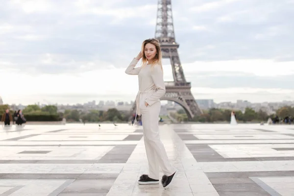 Elegante dama de pie cerca de la Torre Eiffel en un mono blanco . —  Fotos de Stock